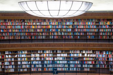 Stockholm Stadsbibliotek veya Halk Kütüphanesi'ndeki rotunda raflarında renkli kitap duvarı.