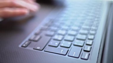 Dizüstü bilgisayarda çalışan genç bir kadın. Klavyedeki tuşlara basan ellerin detaylı görüntüleri