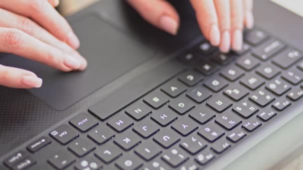 Молодая женщина работает на ноутбуке. Детальная съемка рук, нажимающих кнопки на клавиатуре — стоковое видео