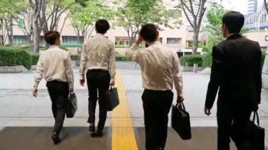 İş adamları Japonya 'da çalıştıktan sonra ofis binasından çıkıyorlar.