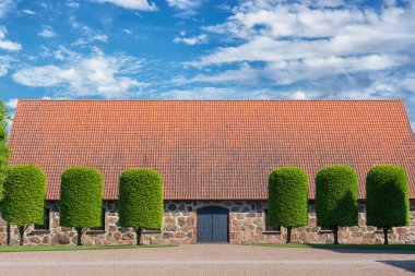 Eski İskandinav tarzı yol, yeşil ağaçlar ve bulutlu mavi gökyüzü.