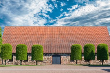 Eski İskandinav tarzı yol, yeşil ağaçlar ve bulutlu mavi gökyüzü.