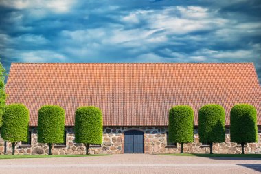 Eski İskandinav tarzı yol, yeşil ağaçlar ve bulutlu mavi gökyüzü.
