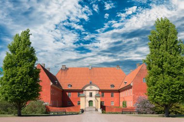 Eski İskandinav tarzı yol, yeşil ağaçlar ve bulutlu mavi gökyüzü.