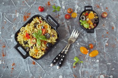 Patlıcan, zeytin ve domates dirsek Makarna Makarna, üzerine taze fesleğen ile süslenmiş bir siyah servis tabağı