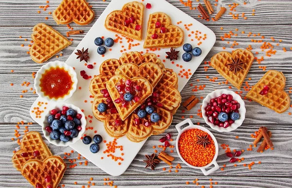 Fresh vegan waffles from red lentils. Healthy gluten-free pastries. Waffles, blueberries, pomegranate, red lentils on white Board