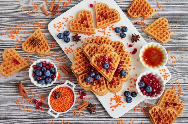 Fresh vegan waffles from red lentils. Healthy gluten-free pastries. Waffles, blueberries, pomegranate, red lentils on white Board