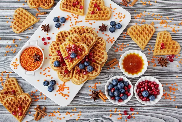 Fresh vegan waffles from red lentils. Healthy gluten-free pastries. Waffles, blueberries, pomegranate, red lentils on white Board