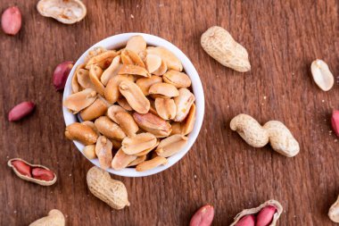 Beyaz kasedeki fıstıklar eski ahşap bir masada duruyor.. 