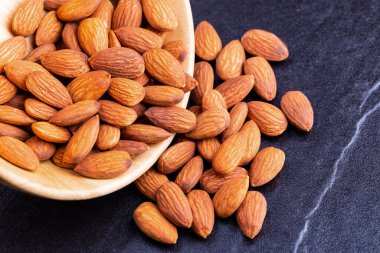 Masadaki tahtadan bir kasede badem. Kopyalama alanı ile badem kavramı.