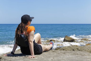 bir kadının güneşin denize bakarak Beach buzlu dinlenme karşı bir şapka ile ön plan 