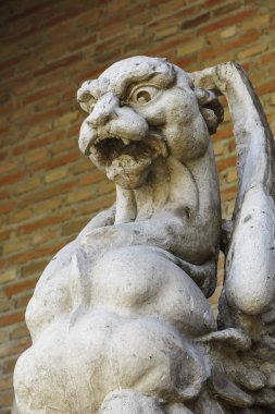 taşa oyulmuş eski bir gargoyle ön planda detay