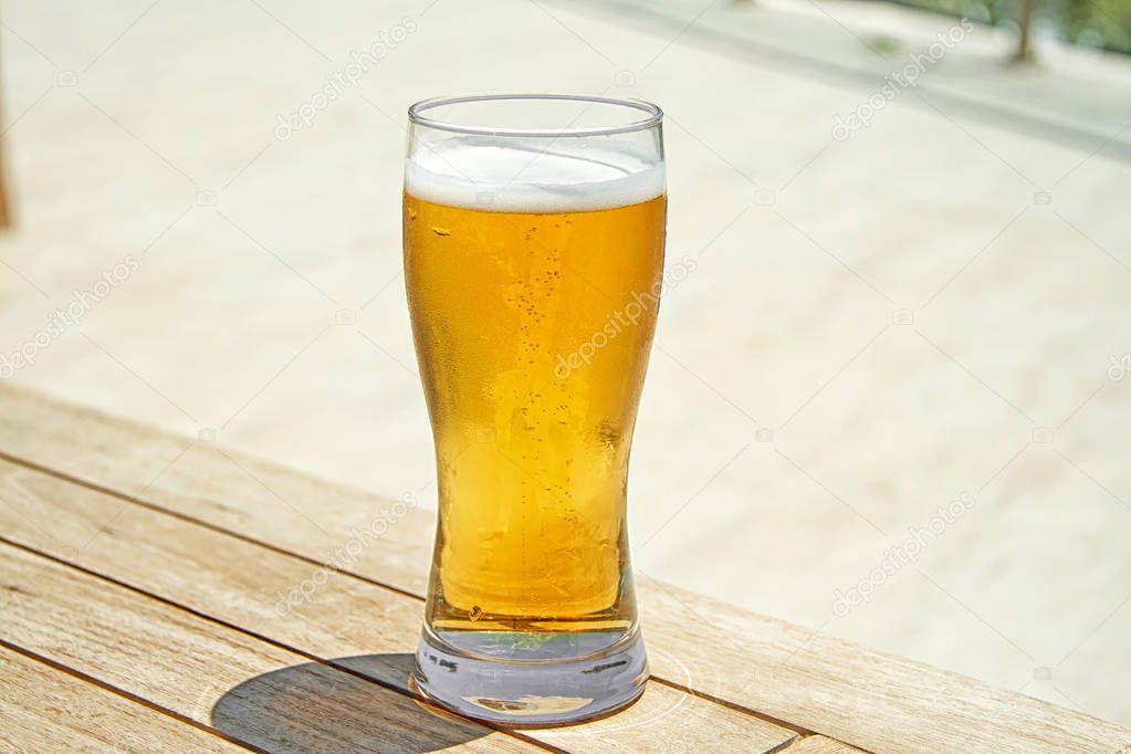 Beer in glass on wooden table. Cold beer on desk.