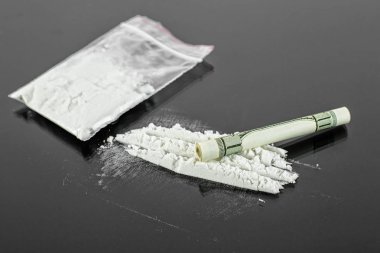 Yüz dolarlık banknot ve kokain yığını siyah arka plan üzerine, closeup haddelenmiş