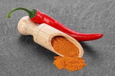 Kırmızı biber biber ve siyah taş masada tahta kaşık toz