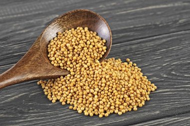 Tahta kaşık üzerinde sarı hardal tohumu. Ahşap arka plan.