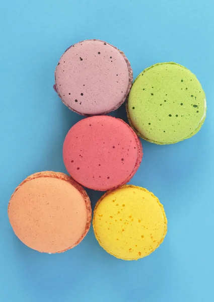 Macarrones de colores con crema sobre fondo azul, vista superior . — Foto de Stock