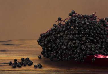 Rustik ahşap masa üzerinde kırmızı metal plaka siyah mürver, 