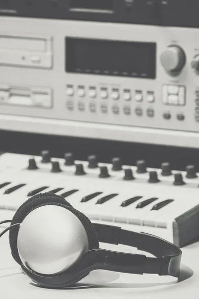 vintage recording studio equipment. headphone, analog keyboard synthesizer and stereo sampler. old black and white film filter