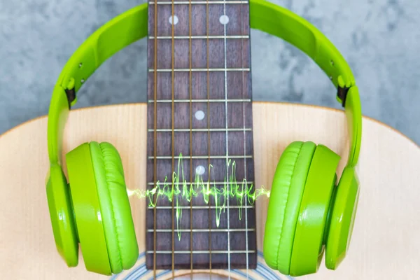 green headphone on acoustic guitar, music background
