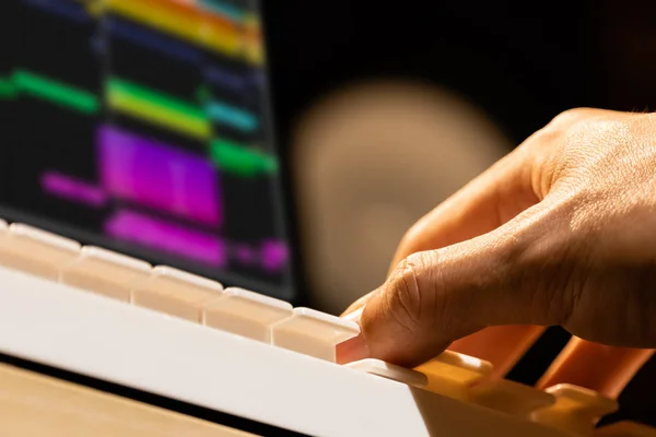musician hands playing on studio midi keyboard with computer monitor, loudspeaker background. recording, music composing and arranging concept.