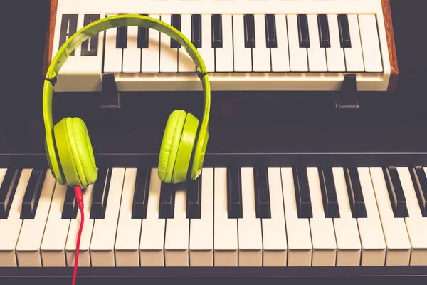 バック グラウンド ミュージックは ピアノの鍵盤に緑色のヘッドフォン — ストック写真