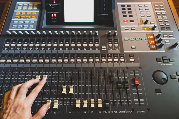 sound engineer hand working on sound mixing console in recording studio. music production, broadcasting concept