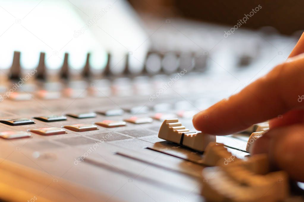 sound engineer hand working on sound mixing console in recording studio. music production, broadcasting concept