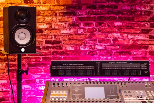 audio mixing console and monitor speaker in recording studio, copy space on brick wall. recording, post production, broadcasting concept