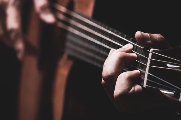 male musician hands playing on acoustic guitar