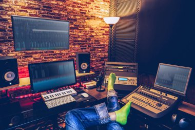 sound engineer, music producer sitting cross-legged and listening final mixdown music in home recording studio clipart