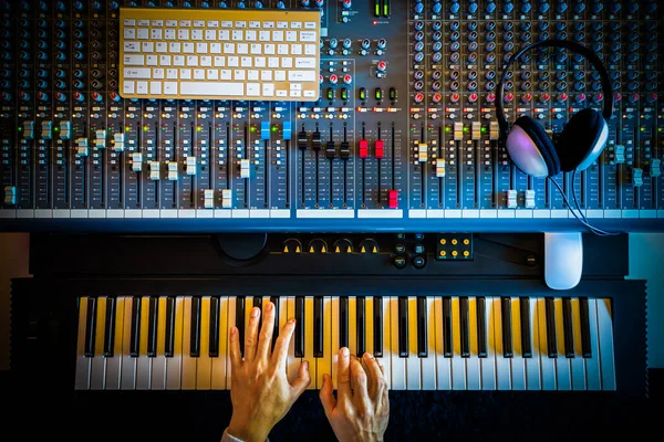 top view of music producer, composer, arranger hands playing midi piano for recording in sound studio. music production concept