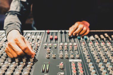 Erkek yapımcı, DJ, ses mühendisi elleri ses karıştırma konsolunun düğmesini ayarlıyor