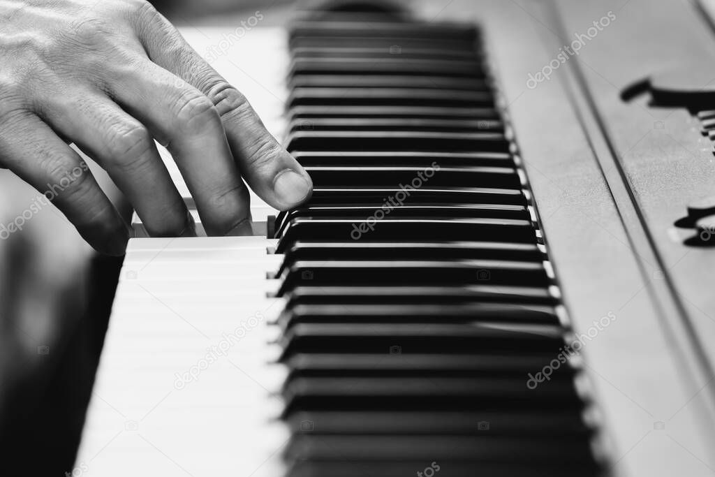 black and white male musician hand playing on piano keys. music concept