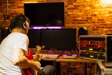Erkek müzisyenin arkası, ev kayıt stüdyosunda elektro gitar çalmayı sever.