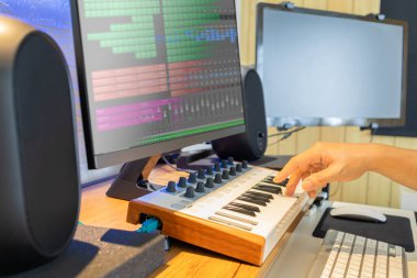 Erkek söz yazarı el bilgisayarda Midi parçalarını kaydetmek için klavye çalıyor. müzik üretim konsepti