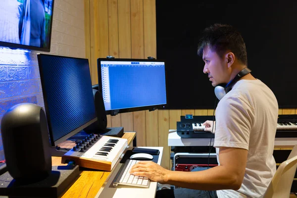 asian professional producer composing, editing music score on movie footage. recording, post production concept
