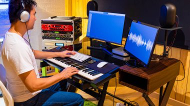 Asyalı erkek yapımcı Midi klavyesinde ve ev stüdyosunda bir şarkı ayarlıyor. müzik üretimi, kayıt, post prodüksiyon teknolojisi kavramı