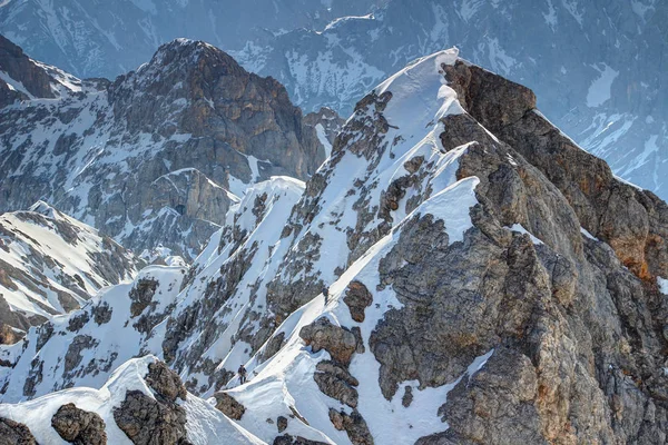 Winzige Bergsteiger erklimmen verschneite Jubilaumsgrat-Route in bayerischen Alpen lizenzfreie Stockbilder
