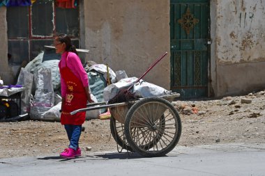 Tibet, Çin, Haziran, 11, 2018. Bir el arabası ile inşaat enkaz küçük köyde Yakra kadınla