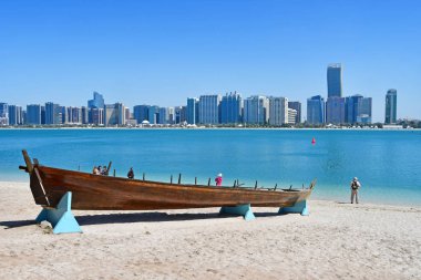 Abu Dabi, BAE Mart, 19, 2019. Güneşli bir gün Abu Dabi gökdelenler arka planda ahşap tekne yakın Persion Körfezi deposunda insanlar 