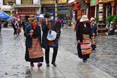 Tibet, Lhasa, Çin, 03 Haziran 2018. İnsanlar yağmurlu havalarda bir yaz gününde antik Barkhor sokak boyunca yürümek