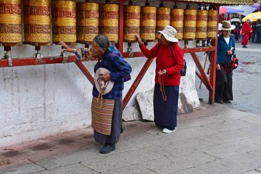 Tibet, Lhasa, Çin, 03 Haziran 2018. Budistler Jokang manastırı yakınındaki Barkor Caddesi'ndeki Lhasa'daki küçük antik Budist manastırlarından birinin yanında ritüel davullar çeviriyor.