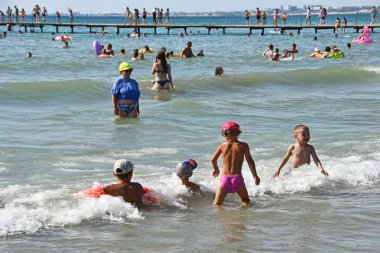 Anapa, Rusya, 18 Temmuz 2018. Anapa'da Karadeniz'in şehir sahilinde bir sürü insan var. Yaz aylarında kıyıya yakın dalgalar da yüzen çocuklar