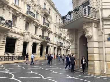 Bakü, Azerbaycan, 10 Eylül 2019. Pınar meydanında insanlar Bakü'deki tarihi binaların yakınında bulutlu bir şekilde yürüyor