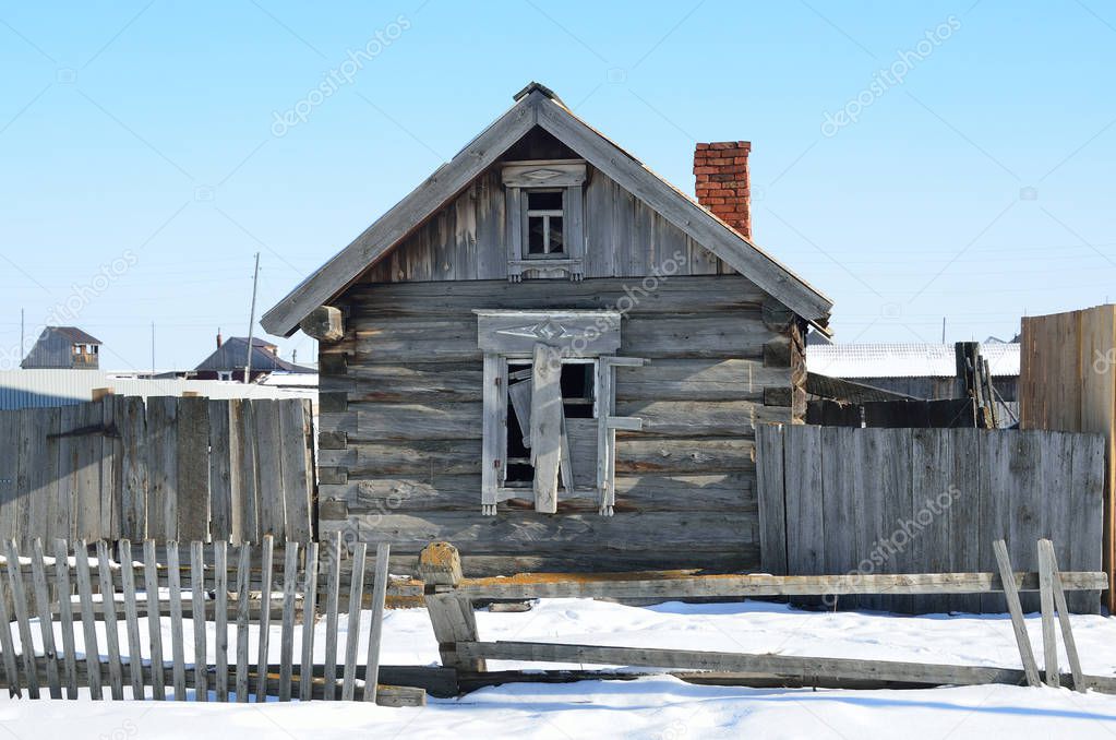 Empty house with boarded up window in the winter