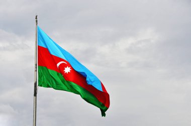 Azerbaycan 'ın ulusal bayrağı gri gökyüzüne karşı bulutlu havada gelişiyor