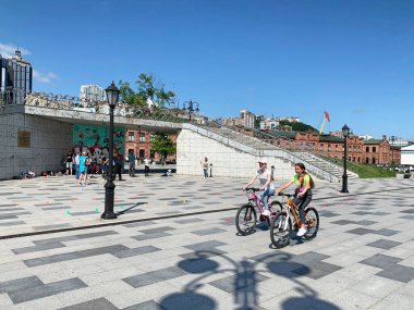 Vladivostok, Rusya, 13 Temmuz, 2020. Vladivostok, güneşli bir günde yaz mevsiminde Tsesarevich setinde bisiklet süren kızlar.