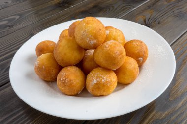 Top beyaz plaka ve ahşap arka plan üzerinde çörek şeklinde