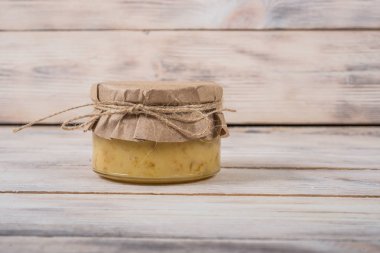 Hafif ahşap arka plan üzerinde bir cam kavanoza tatlım. Arı bal